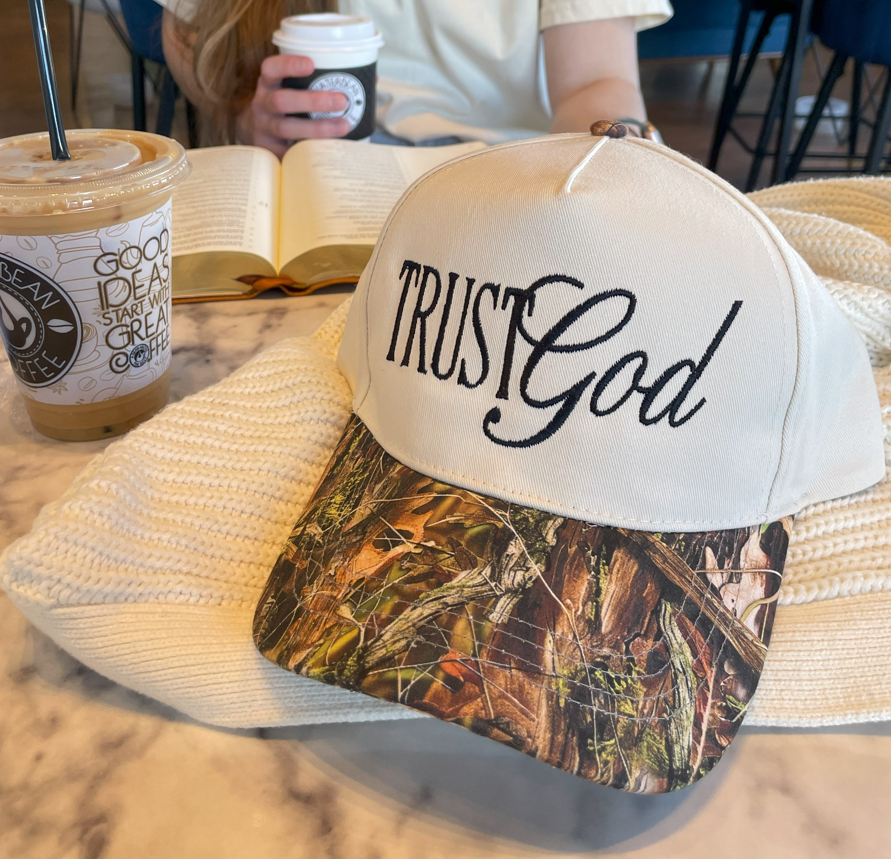 a hat sitting on top of a table next to a cup of coffee