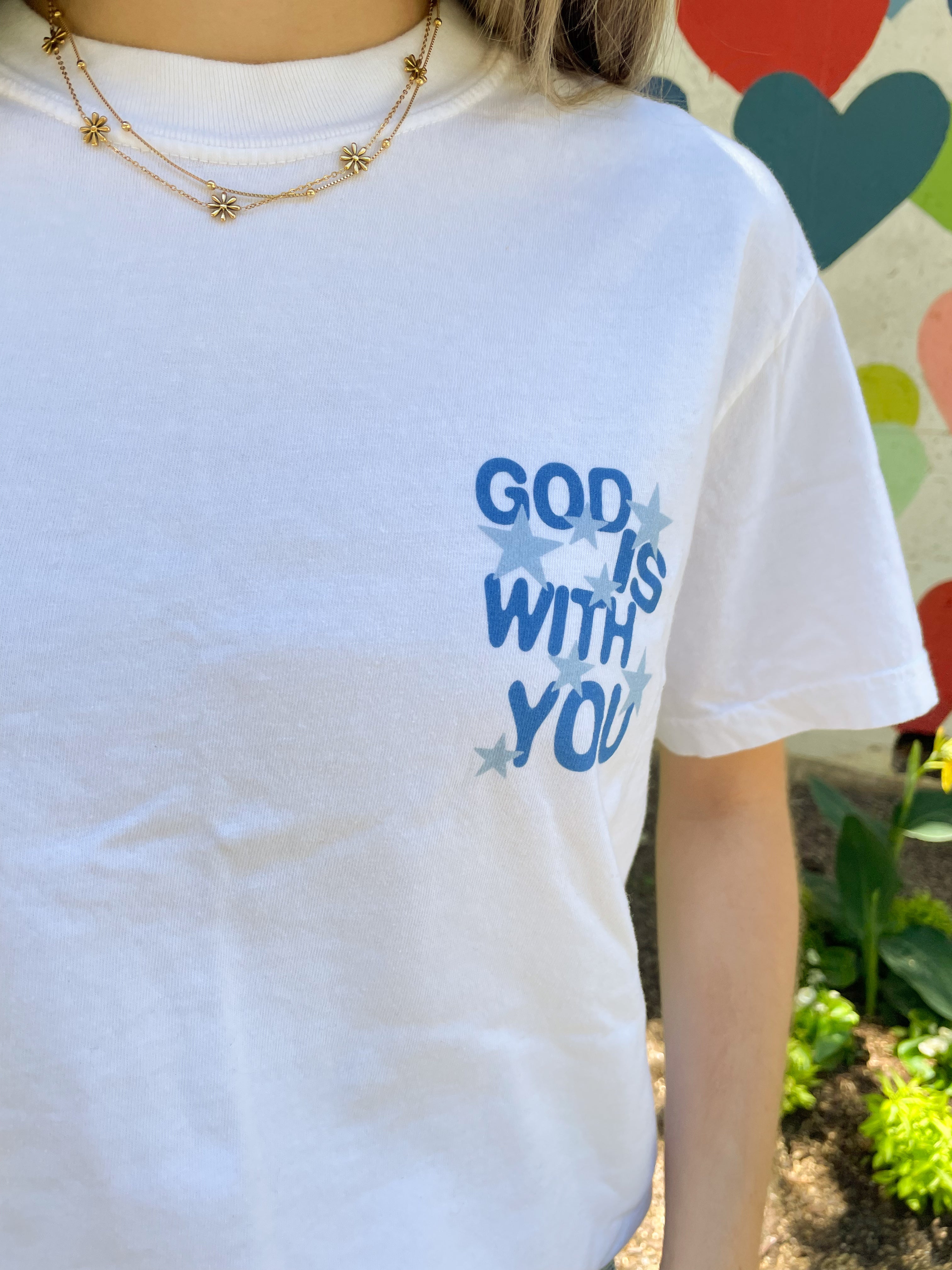a woman wearing a white t - shirt that says god is with you