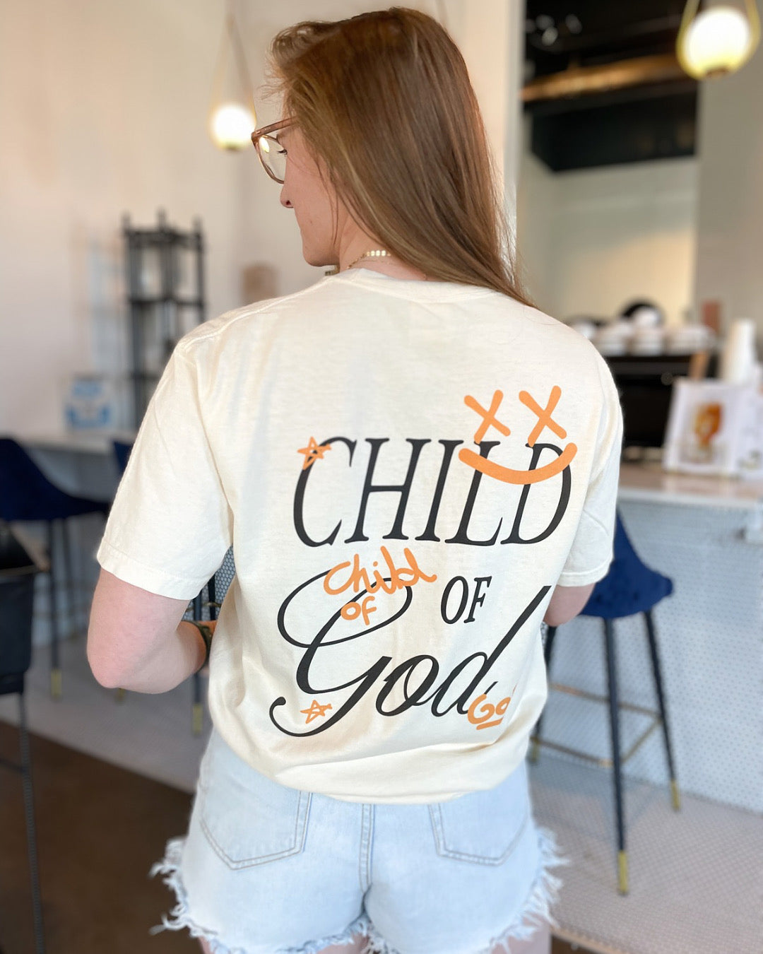 a woman wearing a t - shirt that says child of god