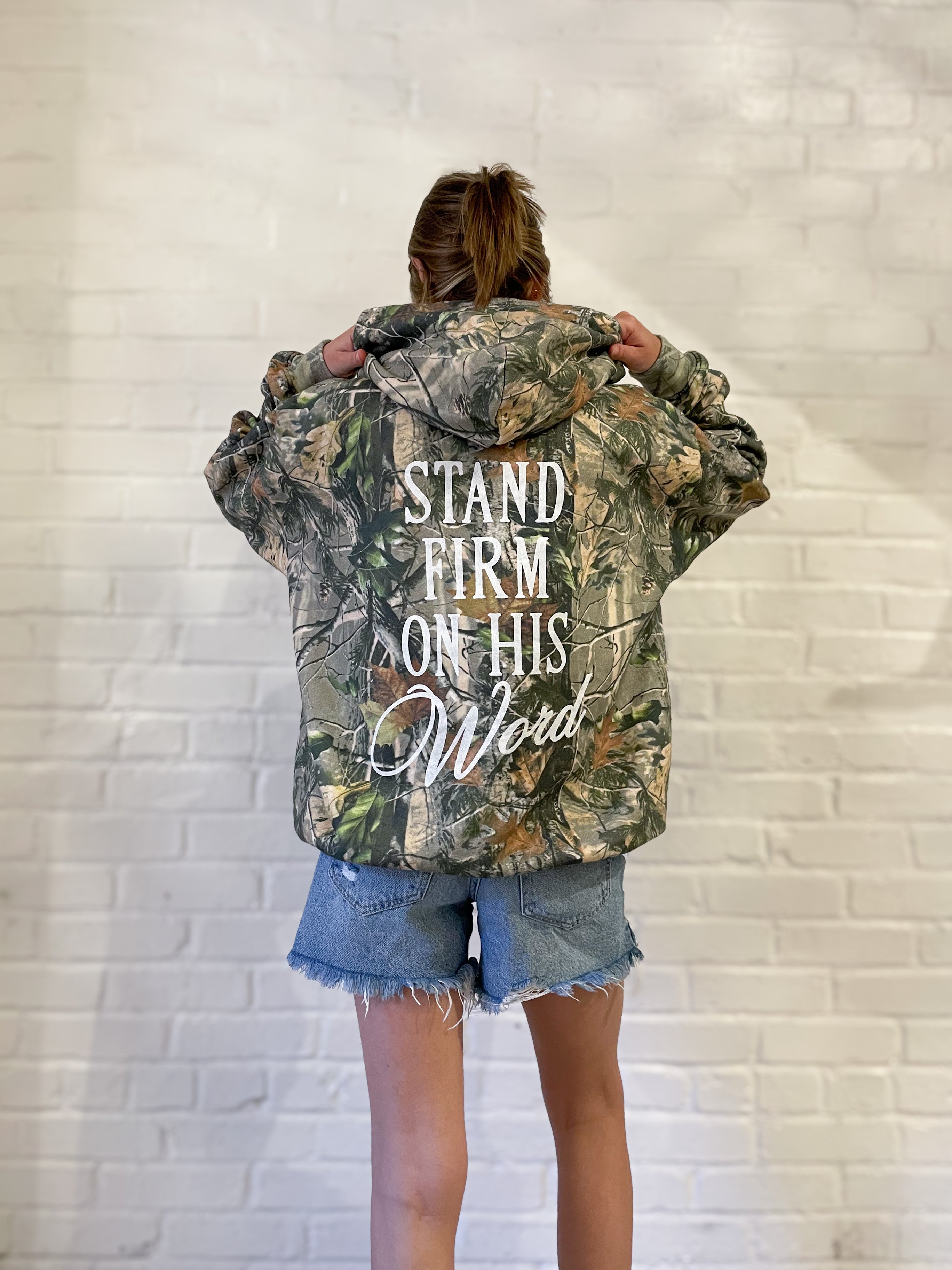 a woman standing in front of a white brick wall
