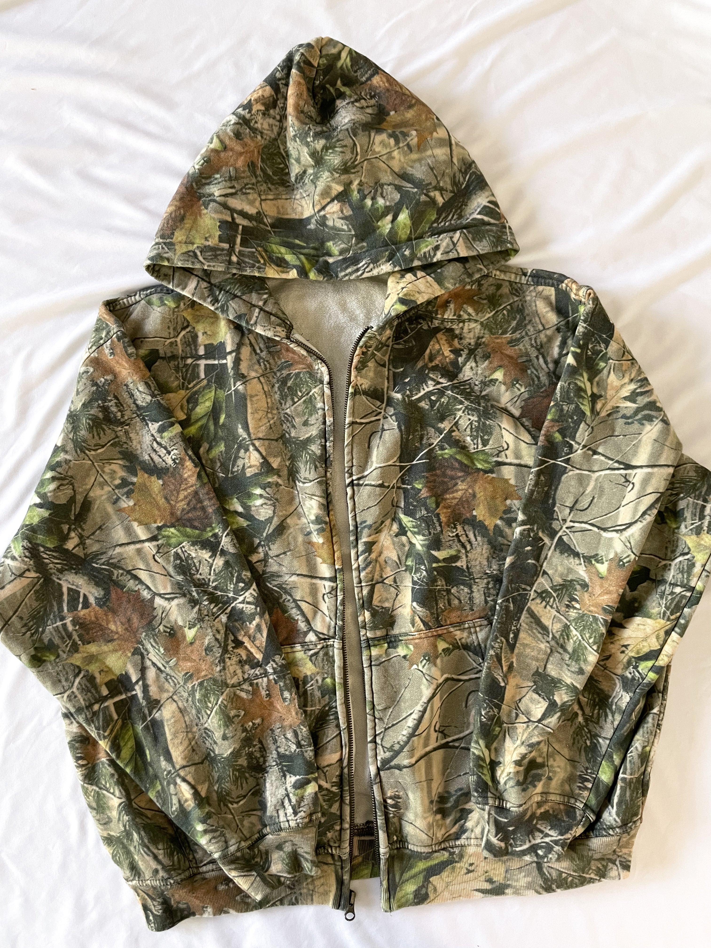 a camouflage jacket is laying on a white sheet