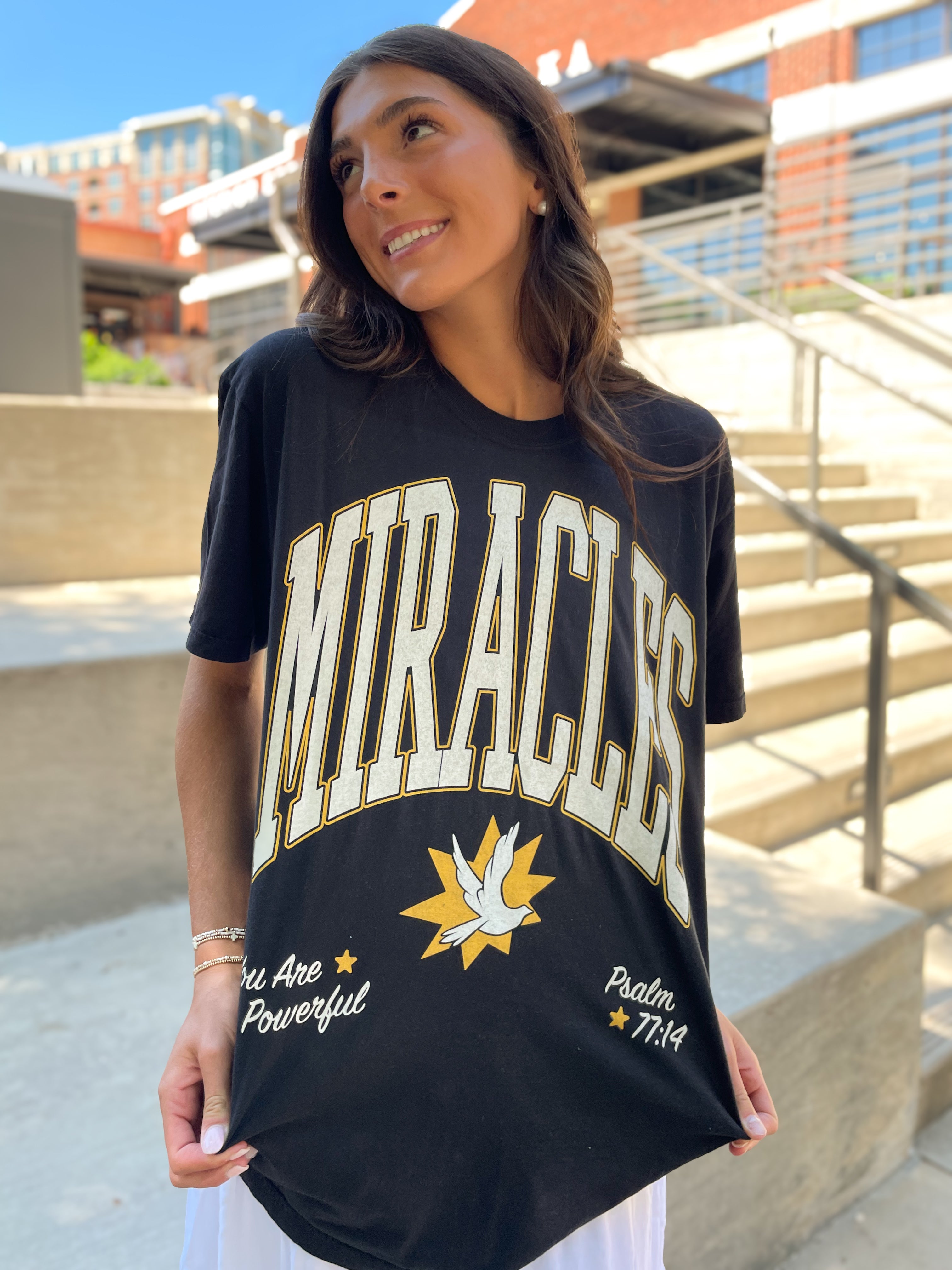 a woman holding up a t - shirt with the word wracles on it