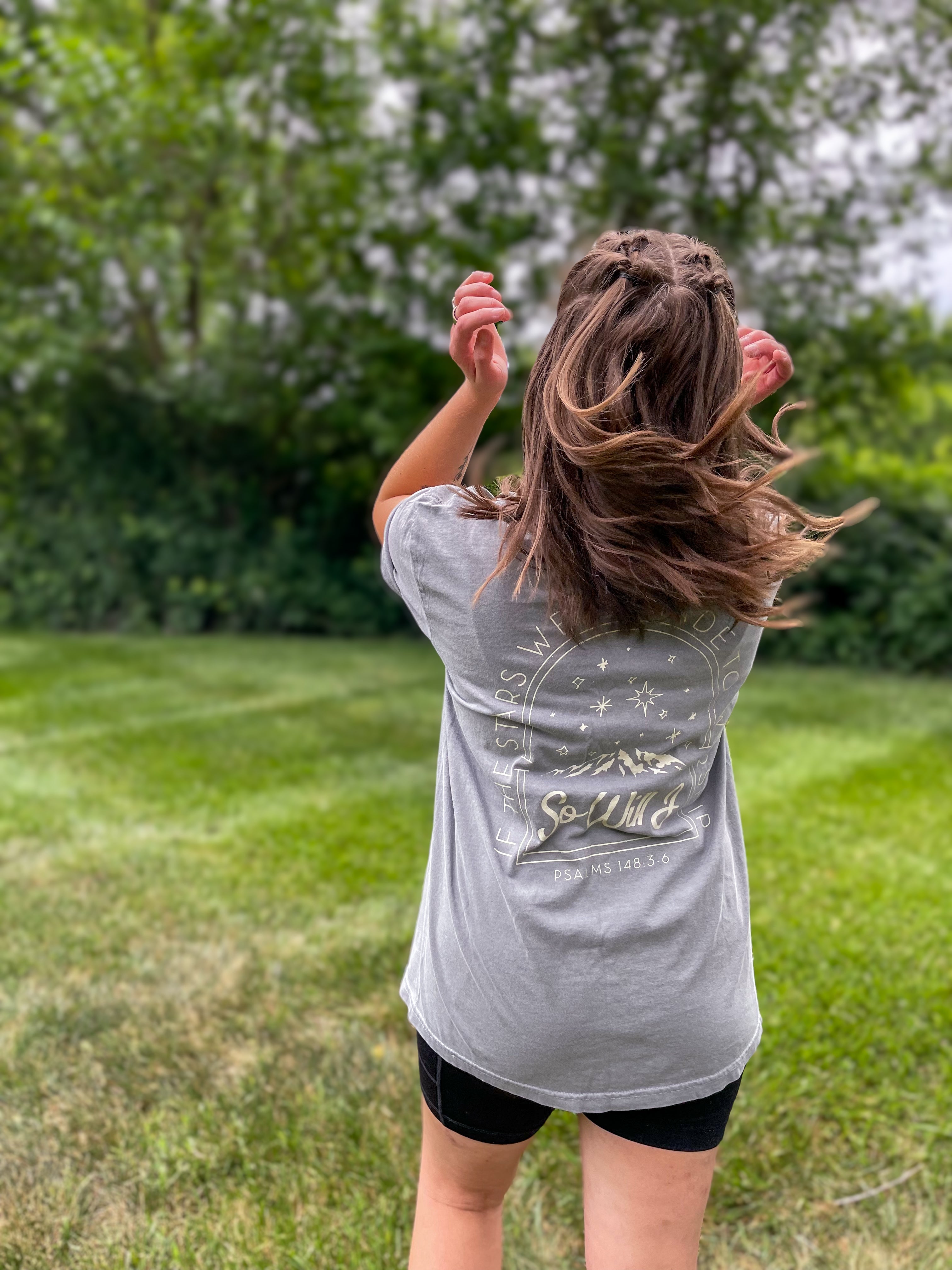 a little girl standing in a field with her hair in the air