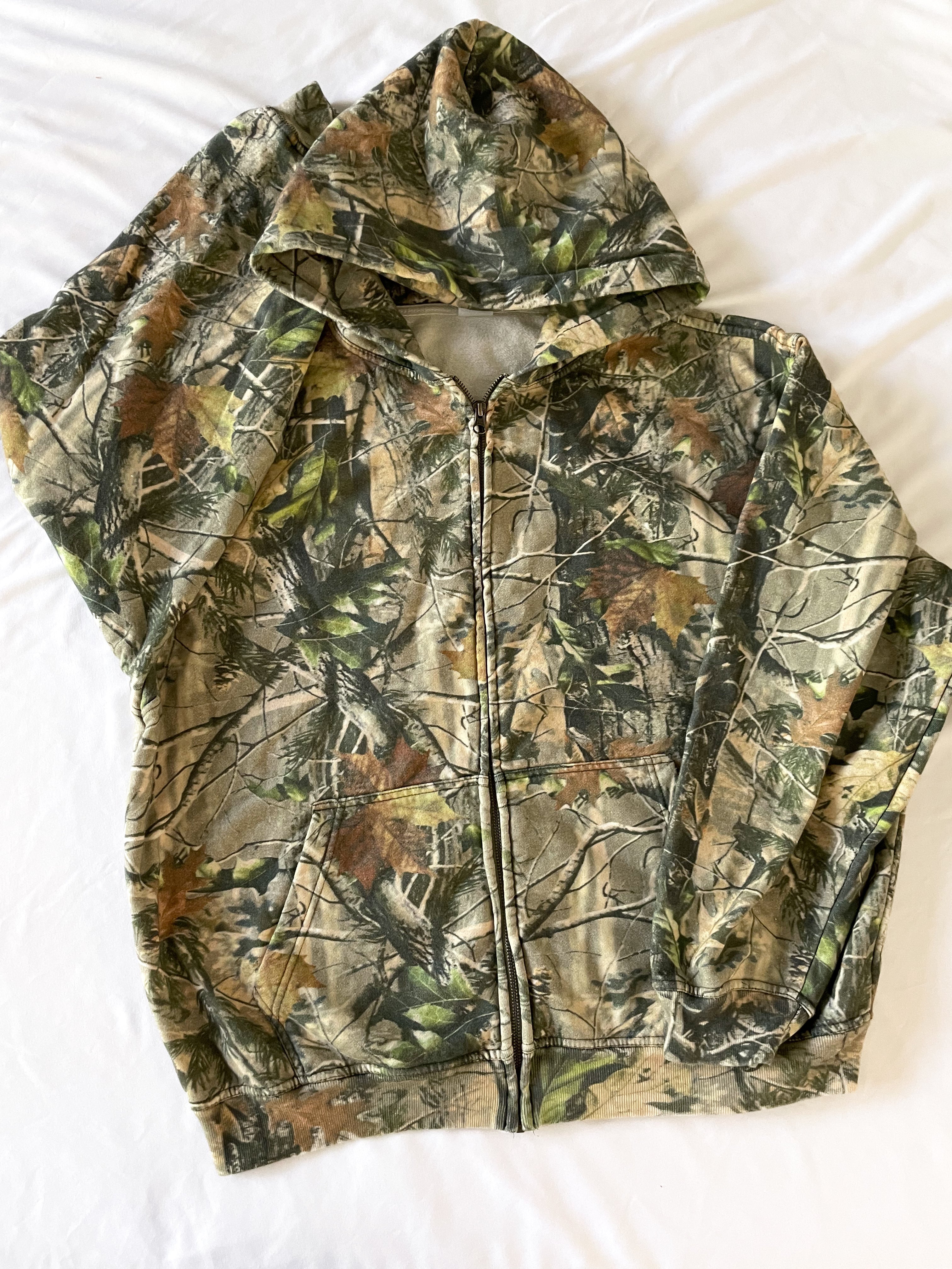 a camouflage jacket laying on top of a bed