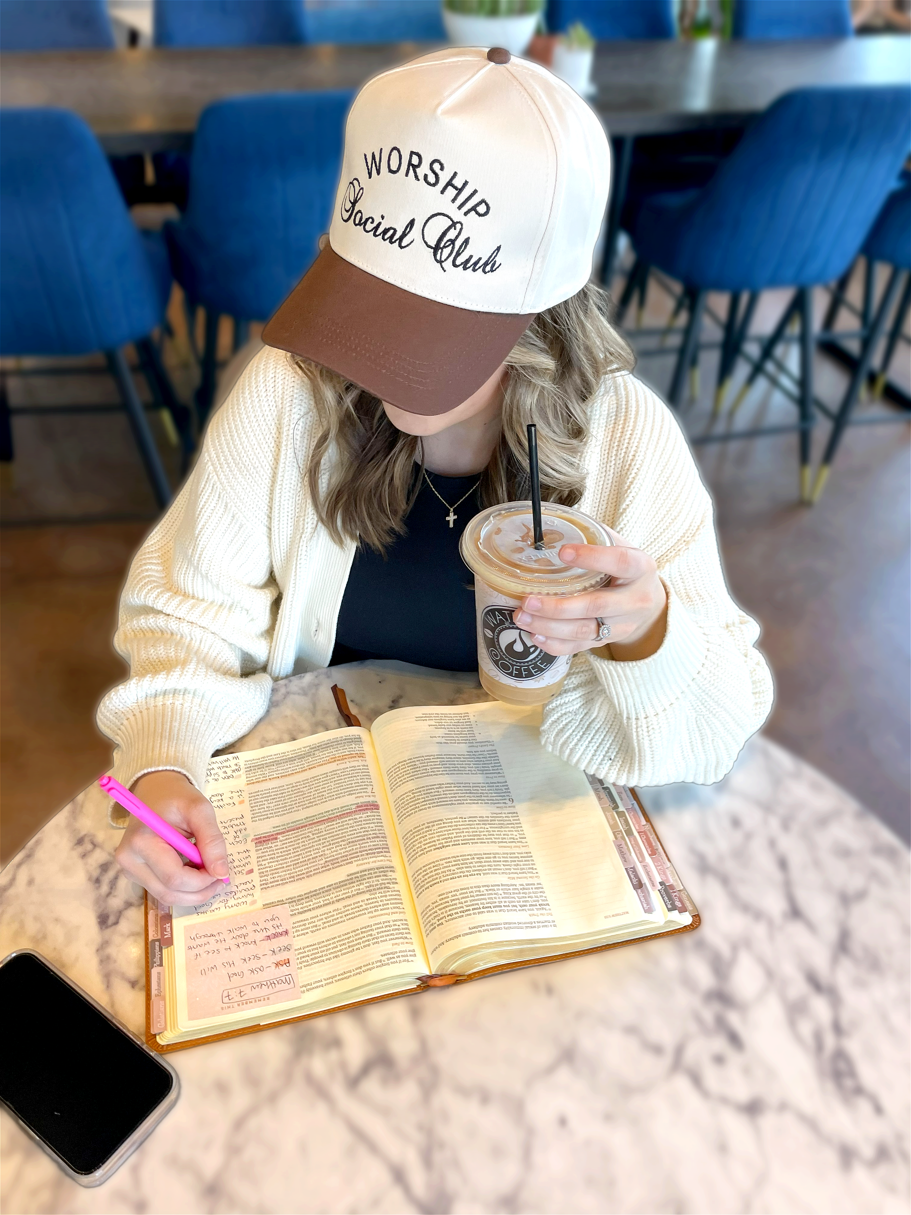 a woman sitting at a table with an open book and a cup of coffee