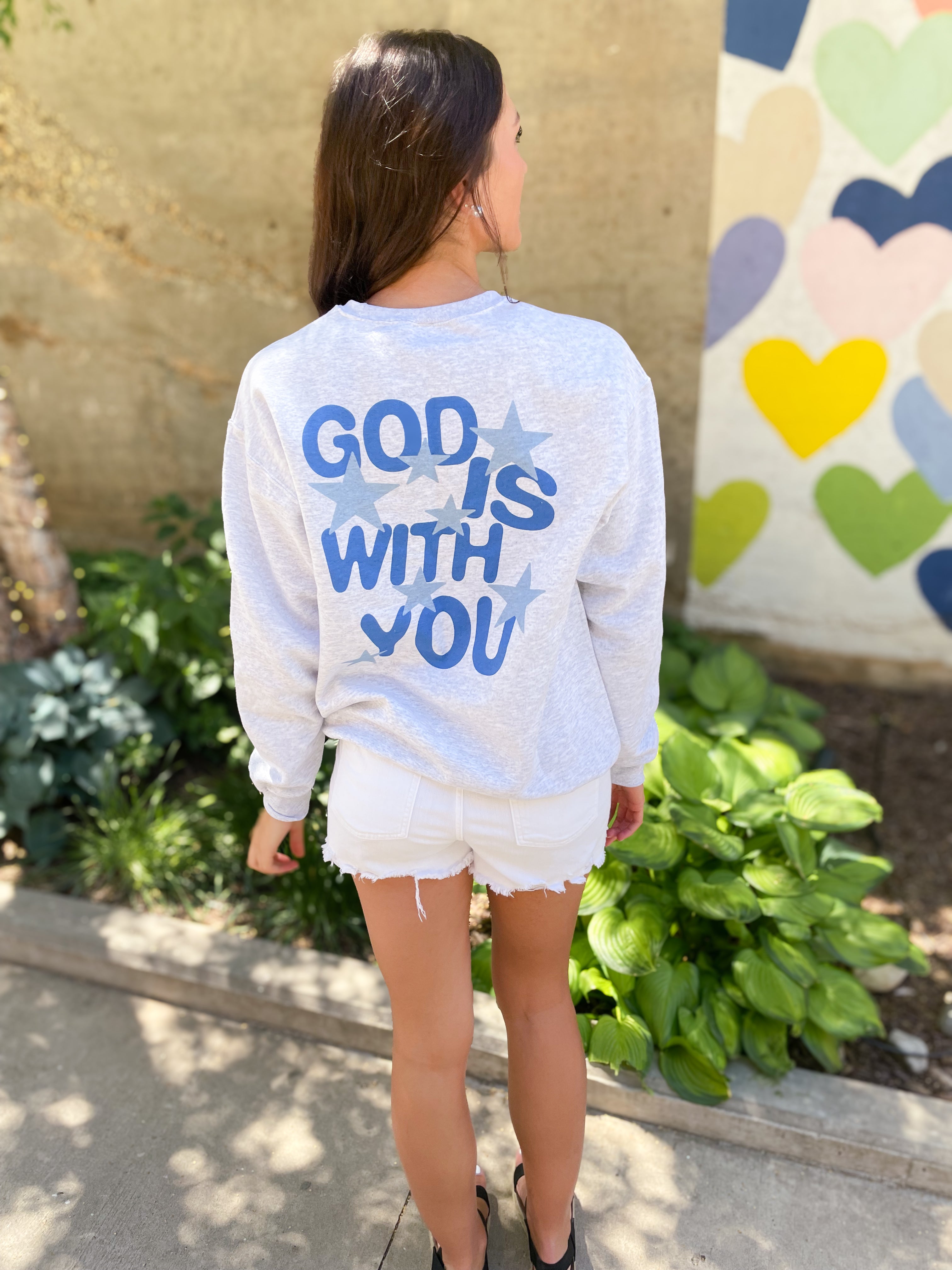 a woman wearing a sweatshirt that says god is with you
