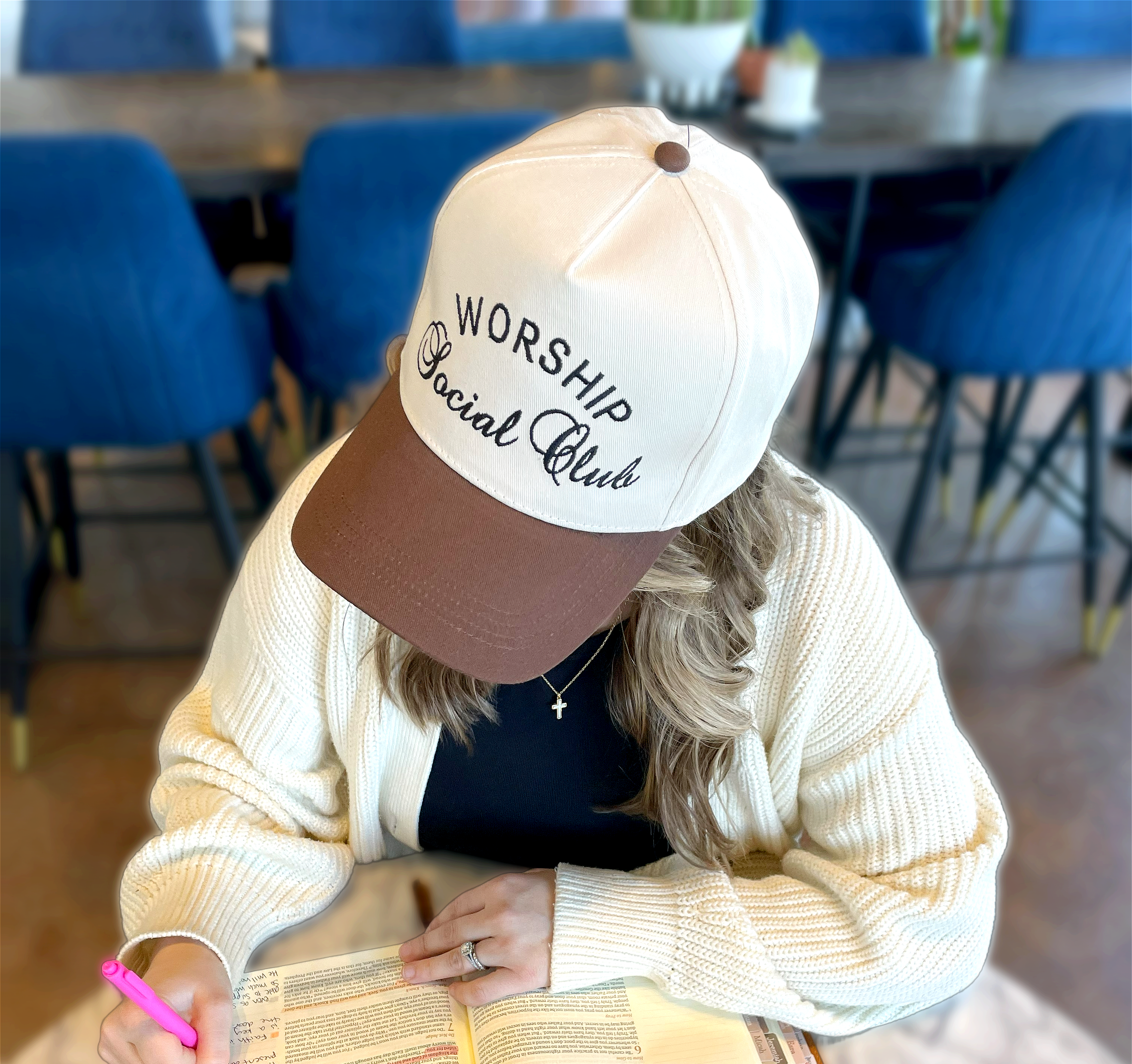 a woman sitting at a table with a book and pen