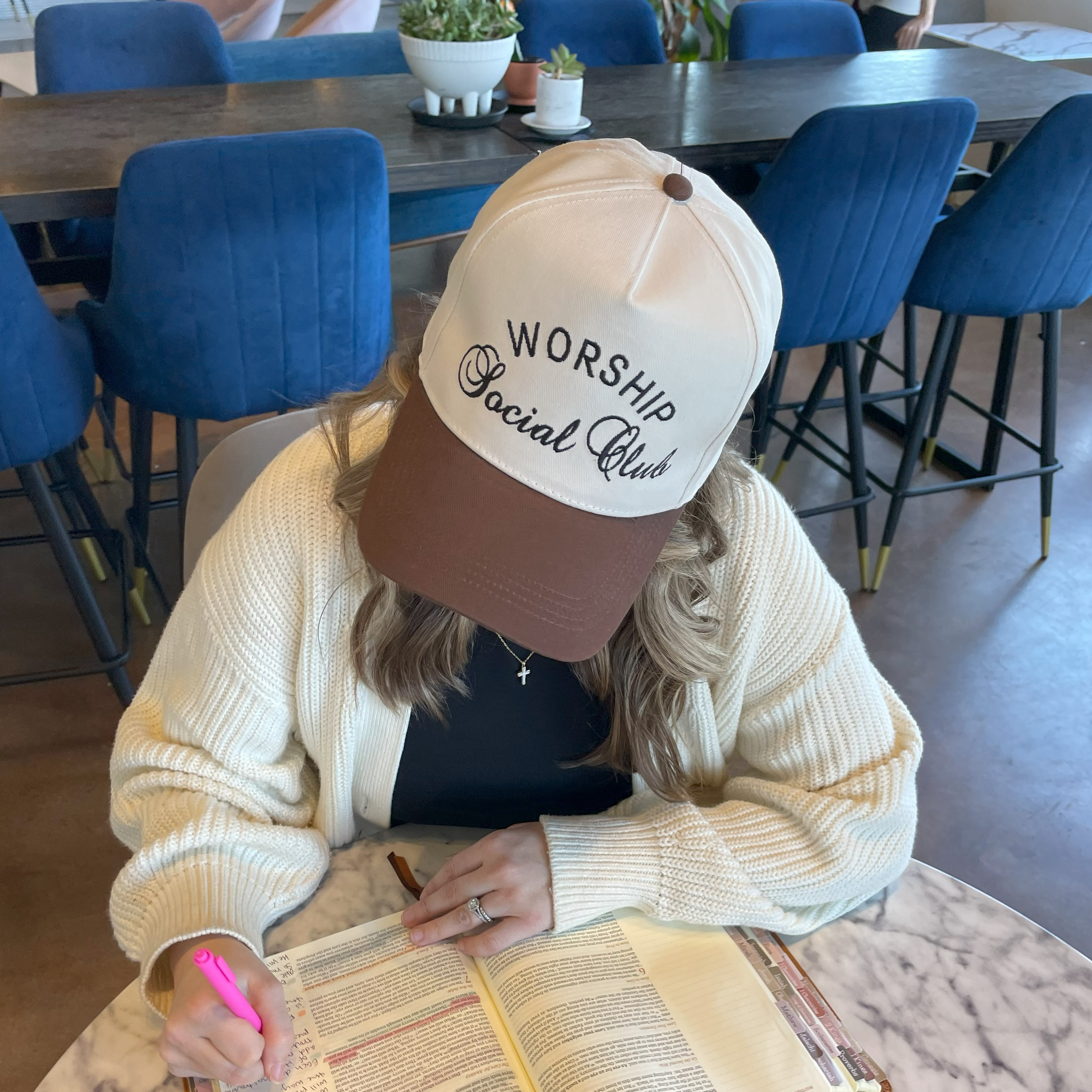 a woman sitting at a table with a book and pen