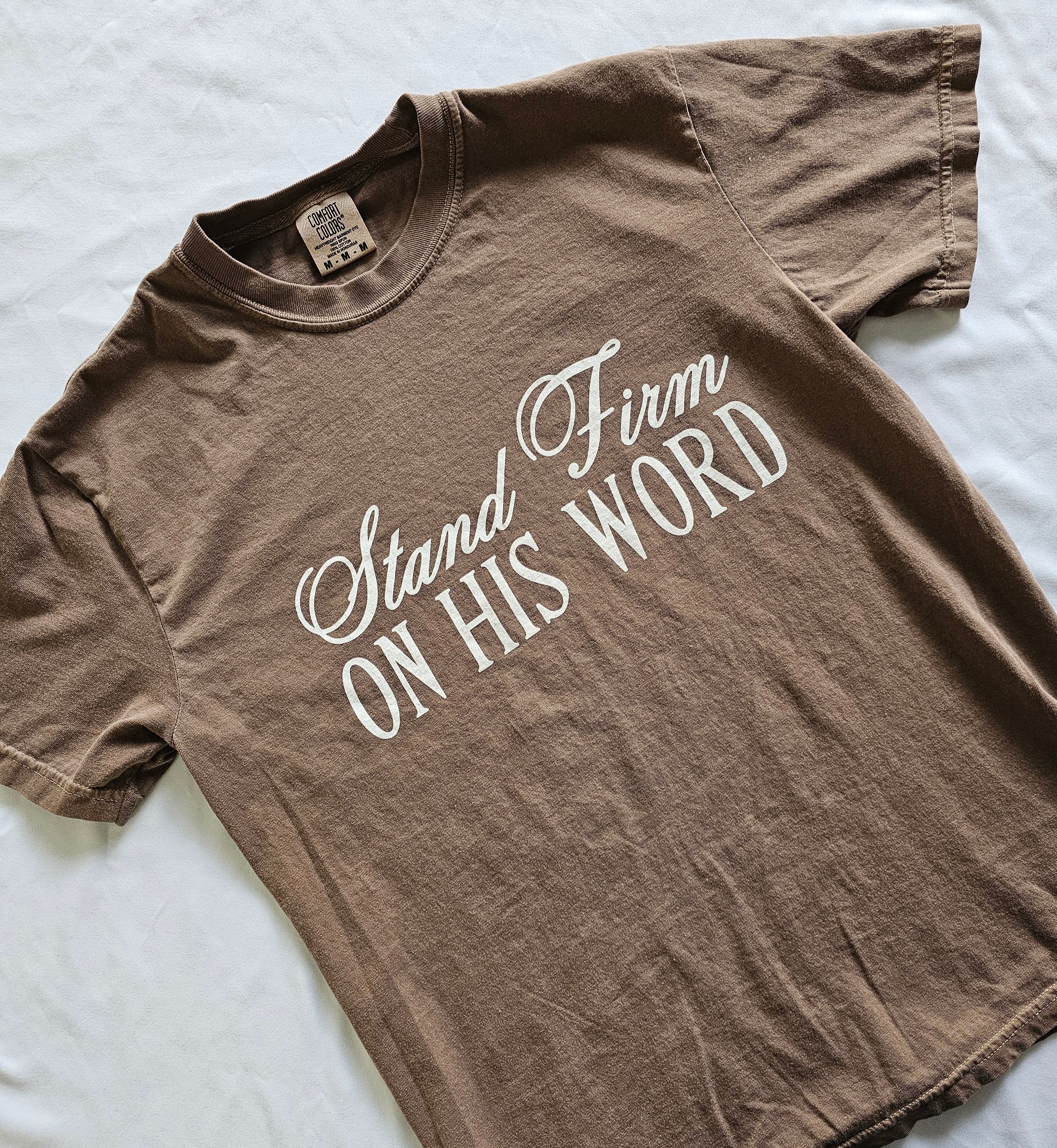 a brown shirt that says stand firm on his word