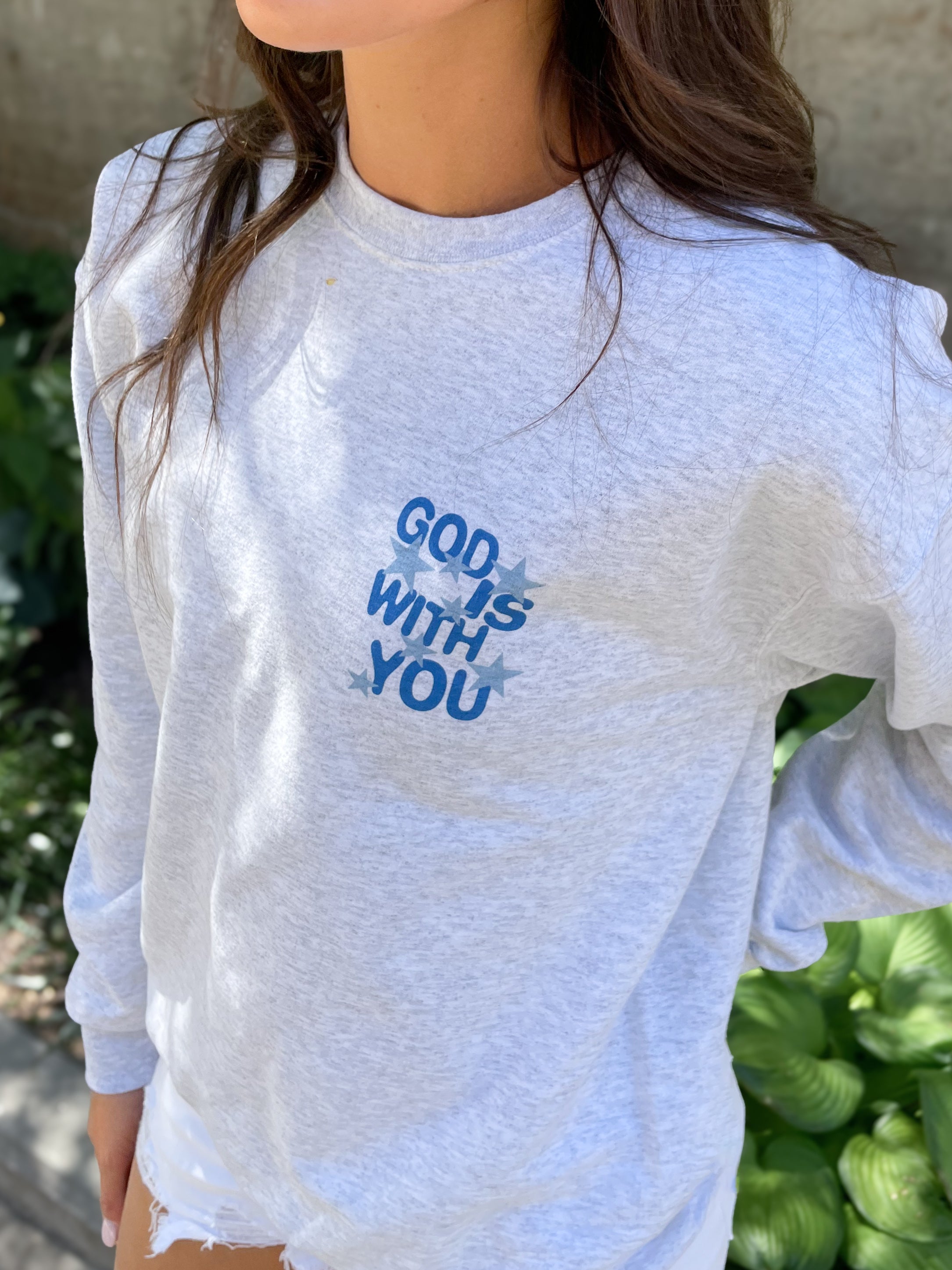 a young girl wearing a white shirt with the words god is with you on it