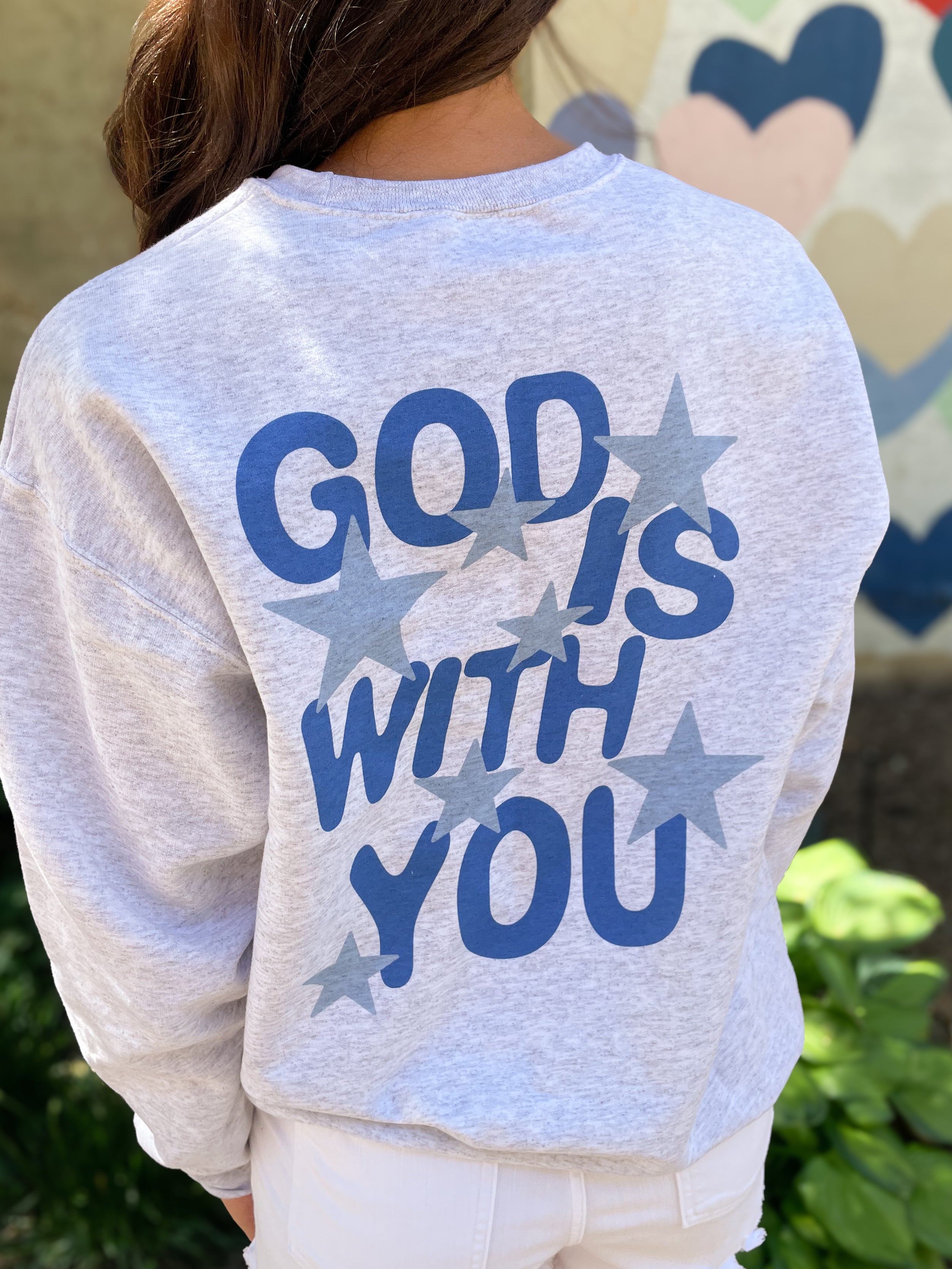 a girl wearing a sweatshirt that says god is with you