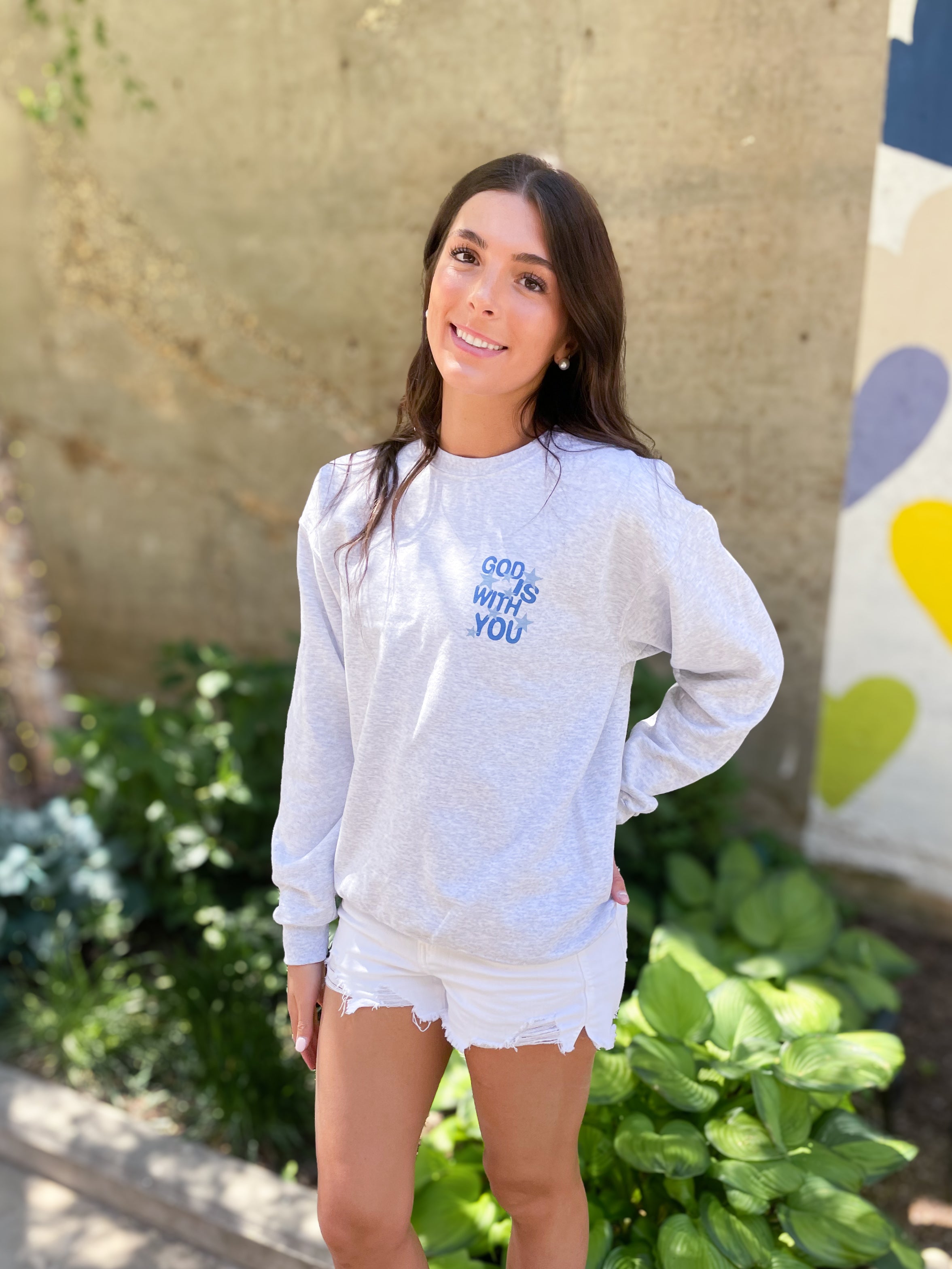 a woman standing in front of a wall wearing a sweatshirt and shorts