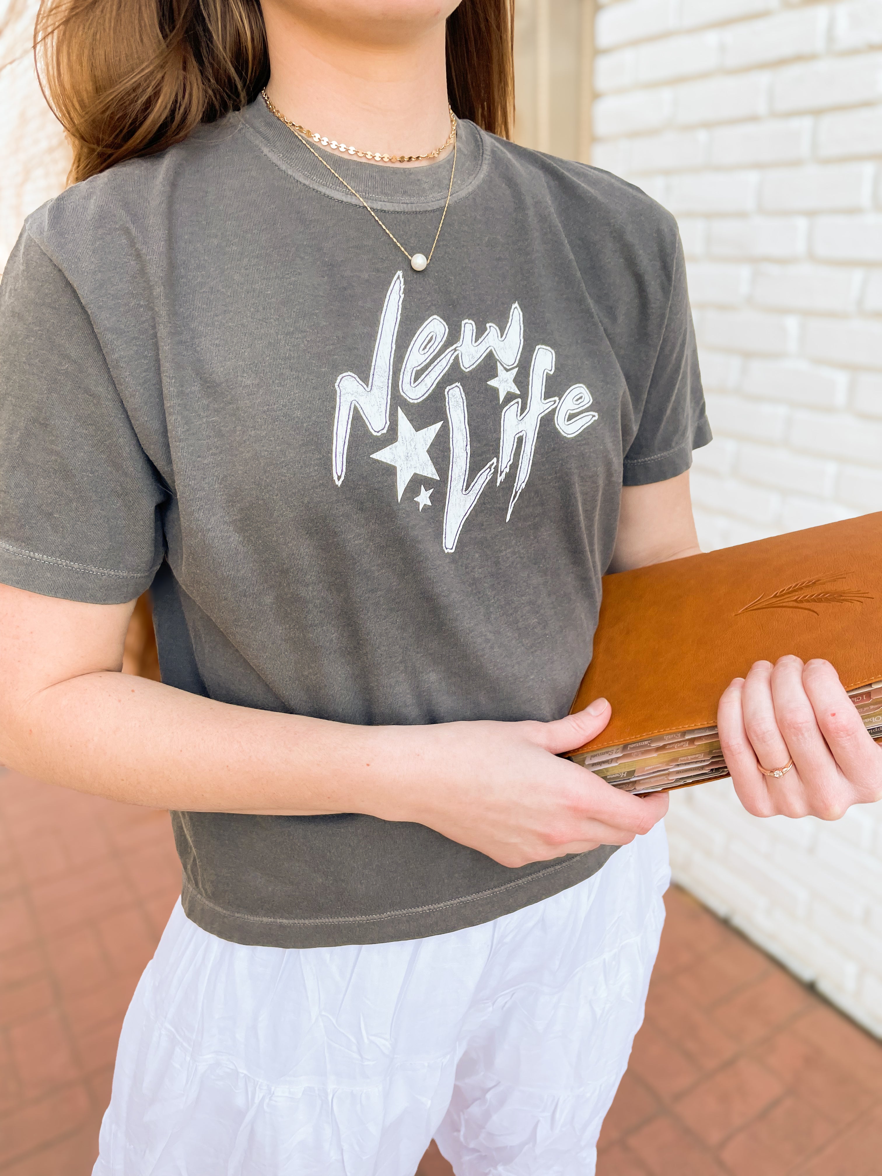 a woman in a gray shirt holding a wooden board